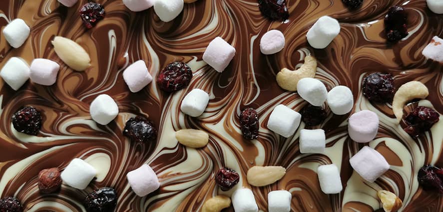 Préparation d'une tablette de chocolat avec des fruits secs et des marshmallows